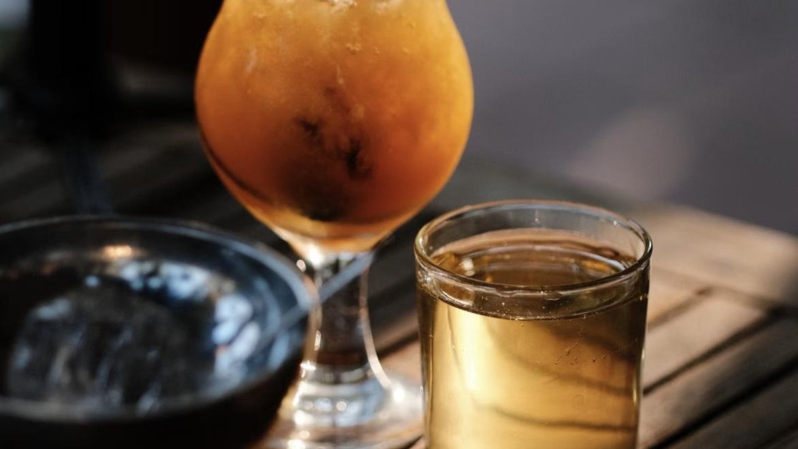Illustrative stock photo of cocktails on a wooden table.