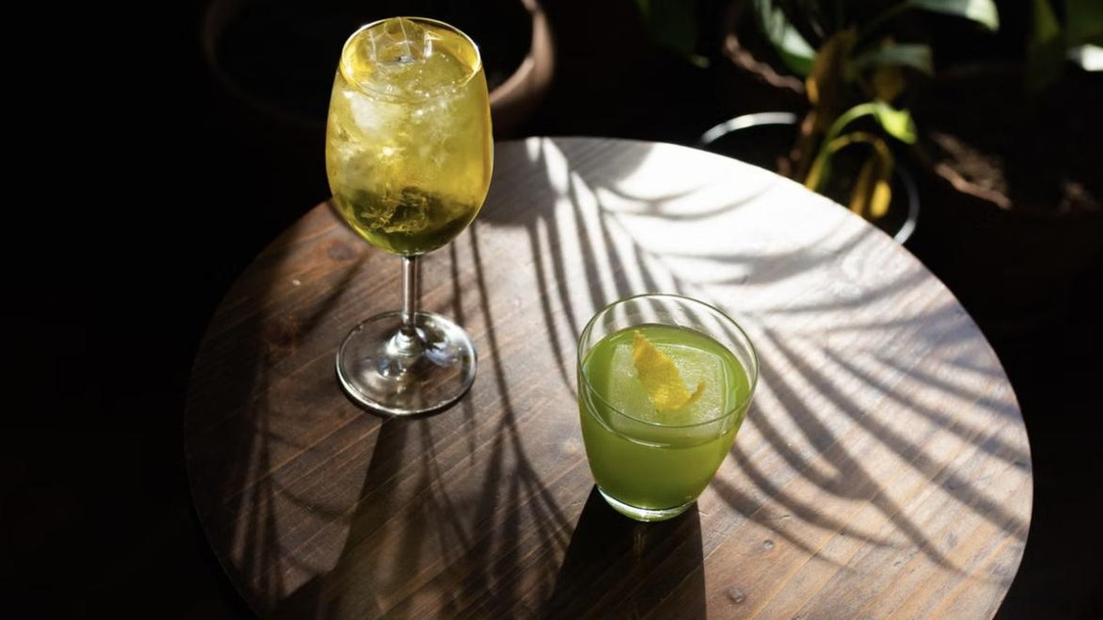 Illustrative stock photo of green cocktails with palm-shadow lighting.