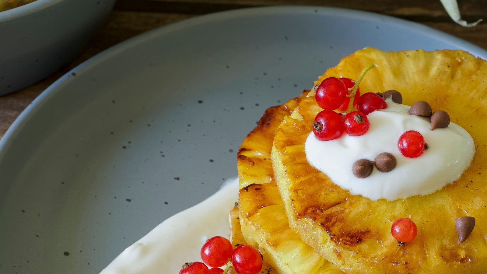 Illustrative stock photo of grilled pineapple with cream and red currants.