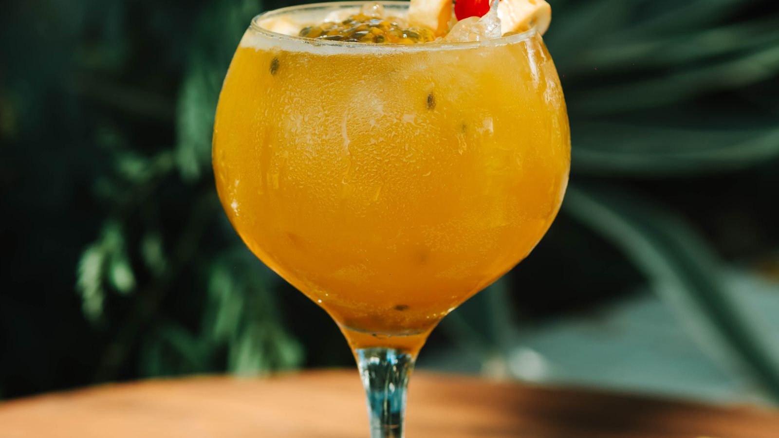 Illustrative stock photo of a tropical cocktail on a sunlit wooden table.